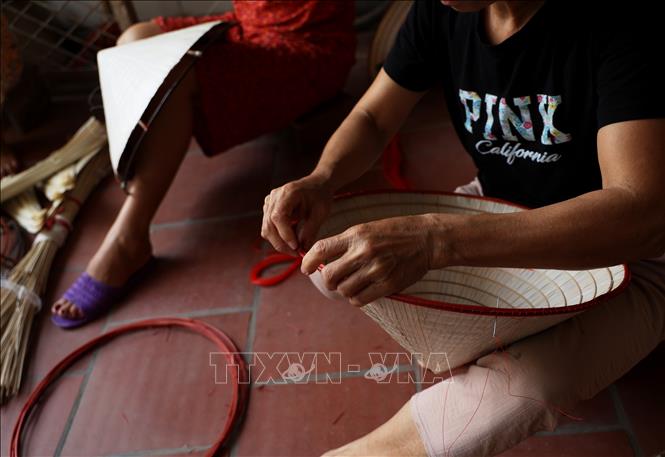 Artisans in the village sew the brim of non la together using thin bamboo sticks. VNA Photo: Hồng Đạt