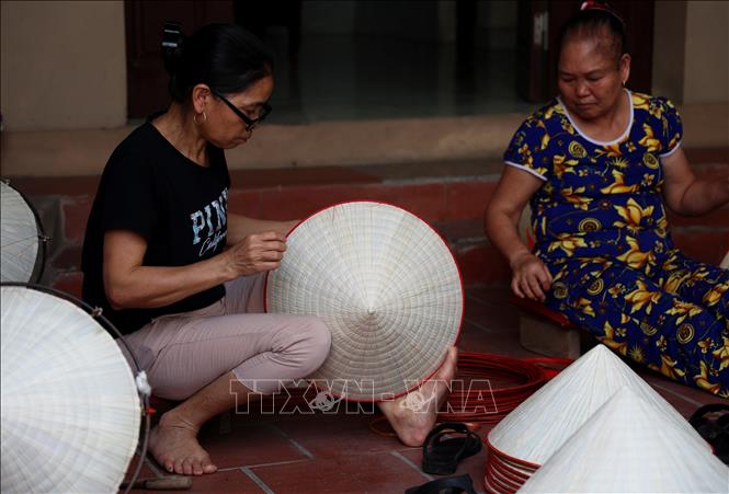 Neighbours often sit together during leisure time to make non la (conical hats). VNA Photo: Hồng Đạt
