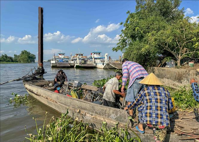 Người dân lên thuyền nhỏ từ phía Cần Thơ để về nhà ở thị xã Bình Minh (tỉnh Vĩnh Long) khi bến đò ngưng hoạt động ngày 6/5. Ảnh: Thanh Liêm - TTXVN