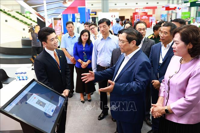 Thủ tướng Phạm Minh Chính tham quan trưng bày về ứng dụng chuyển đổi số trong lĩnh vực ngân hàng. Ảnh: Dương Giang-TTXVN