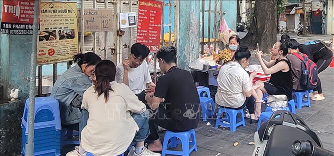 Học sinh, sinh viên hồn nhiên ngồi ăn quán xiên nướng vỉa hè quanh khu vực trường Tiểu học Lê Ngọc Hân, quận Hai Bà Trưng. Ảnh: Phương Anh-TTXVN