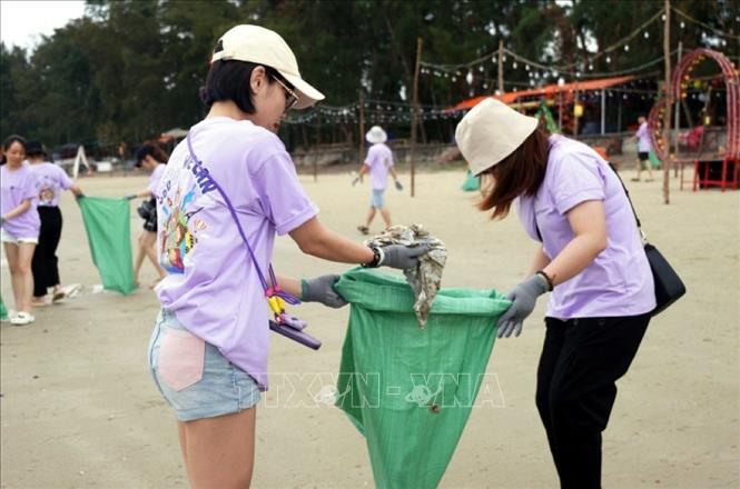 Các thành viên tham gia nhặt rác trên bãi biển. Ảnh: TTXVN phát