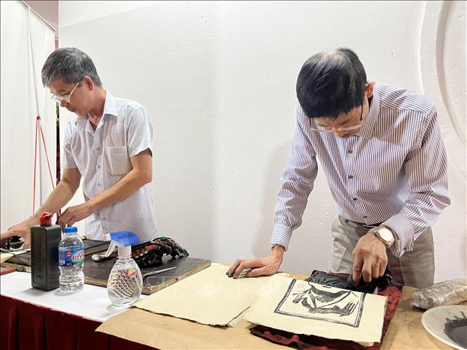 Thực hiện công đoạn in tranh trên giấy Dó. Ảnh: Minh Ngọc - TTXVN phát