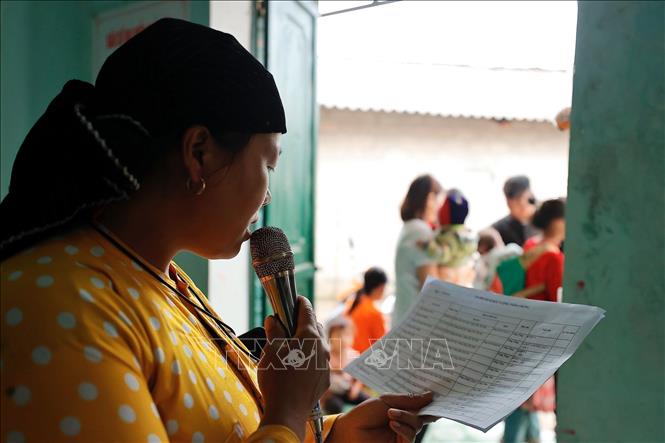 Cô đỡ Mỷ gọi loa thông báo tới các hộ gia đình có trẻ trong độ tuổi đến tiêm vaccine tại nhà văn hoá thôn Cẳng Tằng, xã Lũng Cú, huyện Đồng Văn. Ảnh: Minh Quyết - TTXVN