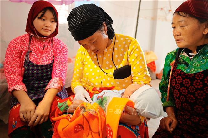 Cô đỡ Mỷ chăm sóc trẻ sơ sinh tại nhà ở thôn Cẳng Tằng, xã Lũng Cú, huyện Đồng Văn. Ảnh: Minh Quyết - TTXVN