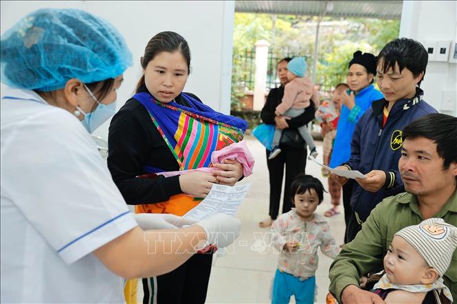 Nhân viên y tế giải thích cho người dân về vaccine chuẩn bị tiêm cho trẻ. Ảnh: Minh Quyết – TTXVN