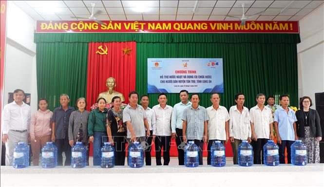 Các tập thể, cá nhân trao tặng nước ngọt cho người dân huyện Tân Trụ. Ảnh: Đức Hạnh - TTXVN 