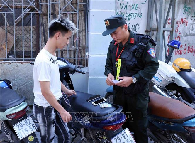 Chiến sĩ thuộc Tổ công tác đặc biệt Công an TP Hà Nội dừng xe, kiểm tra và xử lý 1 trường hợp vi phạm trật tự an toàn giao thông tại tuyến phố Ô Chợ Dừa, quận Đống Đa. Ảnh: Phạm Kiên - TTXVN