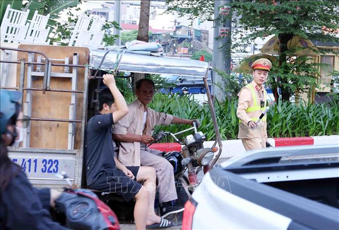 Lực lượng CSGT thuộc Tổ công tác đặc biệt Công an TP Hà Nội dừng xe, kiểm tra và xử lý 1 trường hợp người điều khiển xe ba bánh, bốn bánh tự sản xuất, lắp ráp chở hàng cồng kềnh. Ảnh: Phạm Kiên - TTXVN
