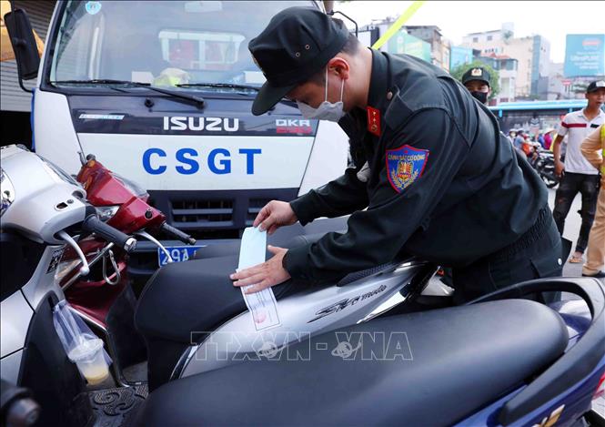 Lực lượng chức năng thuộc Tổ công tác đặc biệt Công an thành phố Hà Nội dán niêm phong tạm giữ phương tiện vi phạm giao thông. Ảnh: Phạm Kiên - TTXVN