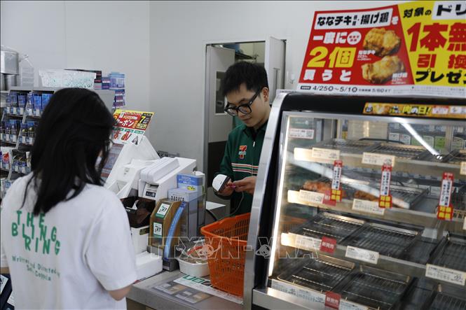 Anh Minh Đức tính tiền cho khách hàng tại cửa hàng tiện lợi 24/24 Seven-Eleven. Ảnh: Xuân Giao - Pv TTXVN tại Nhật Bản