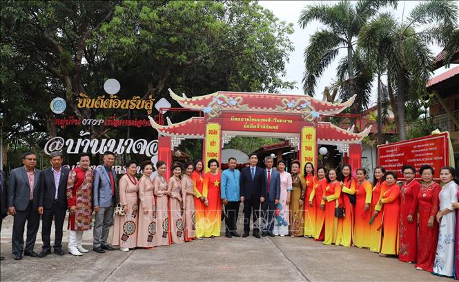 Đại sứ Phạm Việt Hùng và đại diện chính quyền tỉnh Nakhon Phanom chụp ảnh lưu niệm với cộng đồng kiều bào trước cổng Làng hữu nghị Thái Lan - Việt Nam. Ảnh: Đỗ Sinh - P/v TTXVN tại Thái Lan