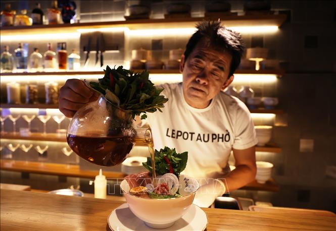 Chef Peter Cuong Franklin pours broth to a special bowl of pho at the restaurant. VNA Photo: Hồng Đạt