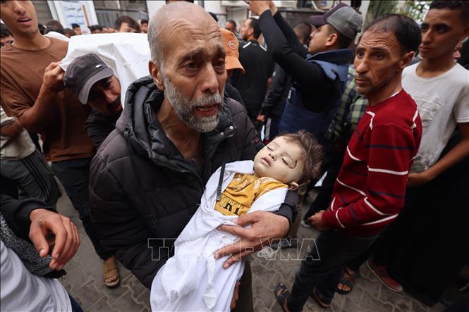Người đàn ông ôm một em nhỏ thiệt mạng trong cuộc không kích của Israel tại thành phố Rafah, Dải Gaza ngày 29/4/2024. Ảnh: AFP/TTXVN