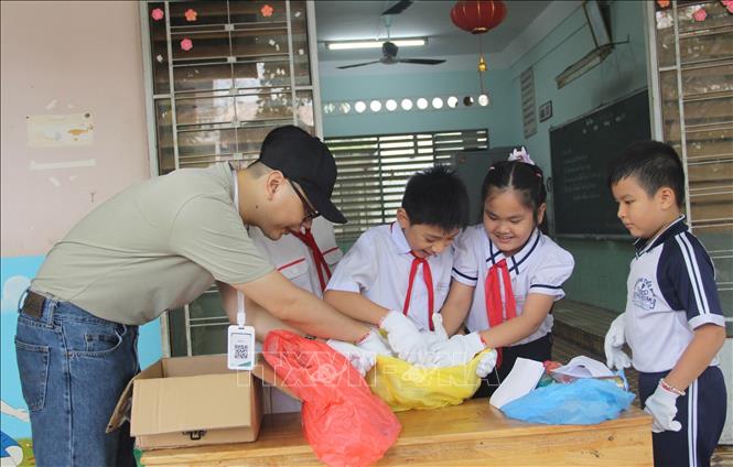 Tình nguyện viên Dự án hỗ trợ các học sinh trường Tiểu học Xương Huân 2 cách nhận biết và phân loại rác tại nhà đúng cách. Ảnh: Phan Sáu - TTXVN