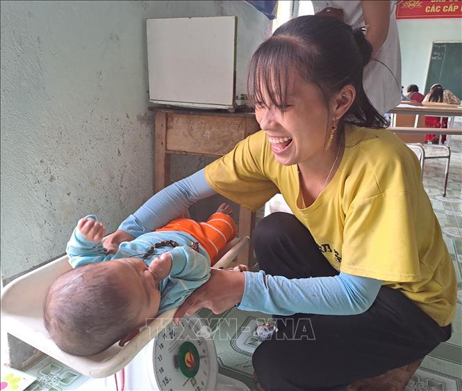 Một bà mẹ kiểm tra cân nặng cho con tại trạm y tế xã Lũng Cú (Đồng Văn, Hà Giang). Ảnh: Đức Thọ - TTXVN