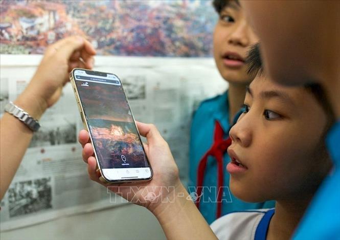 Học sinh thích thú tìm hiểu về lịch sử qua công nghệ thực tế ảo tăng cường được tích hợp trong tranh. Ảnh: Quốc Dũng - TTXVN