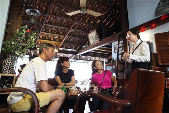 Du khách nước ngoài nghe giới thiệu về lịch sử của quán cà phê Đỗ Phủ và những câu chuyện về các chiến sĩ biệt động Sài Gòn. Ảnh: Thanh Tân - TTXVN