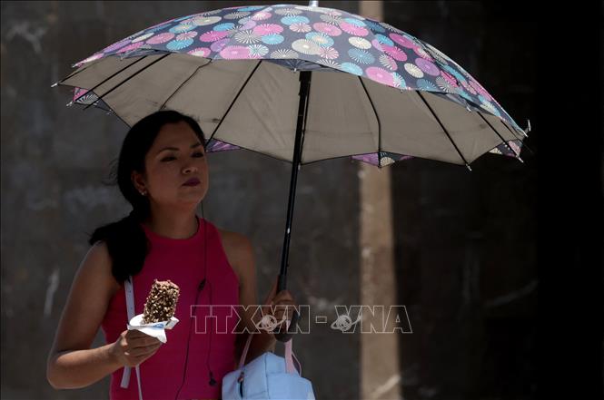 Người dân di chuyển dưới trời nắng nóng tại Guadalajara, Mexico ngày 23/5/2024. Ảnh: AFP/TTXVN