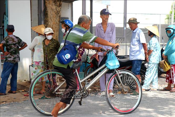 Người khuyết tật bán vé số vừa nhận suất cơm miễn phí từ quán cơm Từ Tâm. Ảnh: Thu Hiền - TTXVN