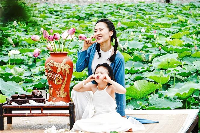 Khoảnh khắc dễ thương của hai mẹ con bên những bông sen nở sớm ở Hồ Tây (Hà Nội). Ảnh: Khánh Hoà - TTXVN