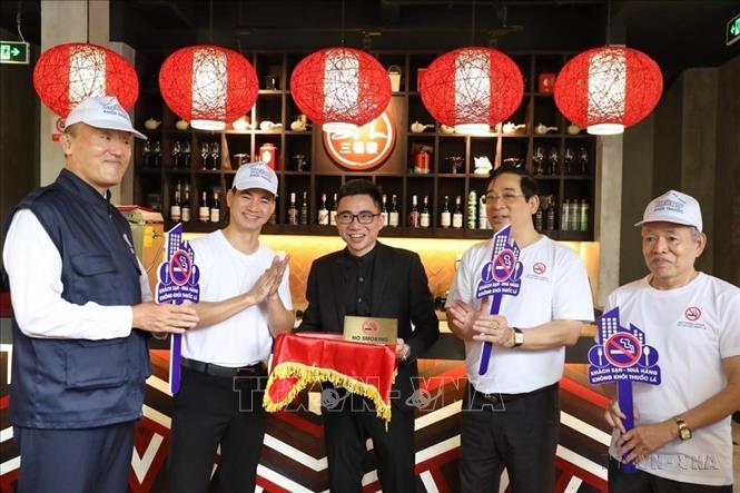 Đại biểu tham gia gắn biển cấm hút thuốc lá tại một số khách sạn, nhà hàng ở Hà Nội trong Lễ phát động Chiến dịch xây dựng khách sạn, nhà hàng không khói thuốc tại Thành phố (2021). Ảnh: Minh Quyết - TTXVN