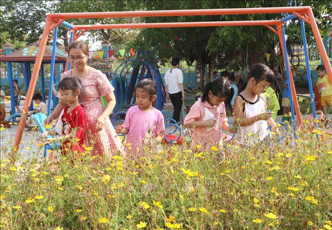 Cô giáo Trường Mầm non Sơn Ca (phường Tân Ngãi, thành phố Vĩnh Long, tỉnh Vĩnh Long) hướng dẫn trẻ thu hoạch hạt để nhân giống hoa. Ảnh: Lê Thúy Hằng - TTXVN