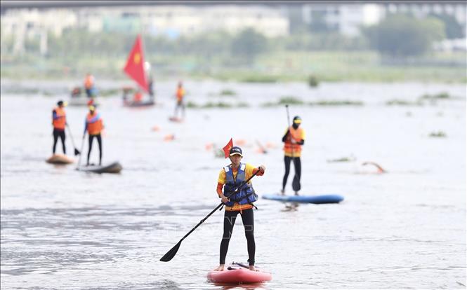 Các vận động viên chuyên nghiệp trình diễn bộ môn Ván chèo đứng trên sông Sài Gòn. Ảnh: Thanh Vũ-TTXVN
