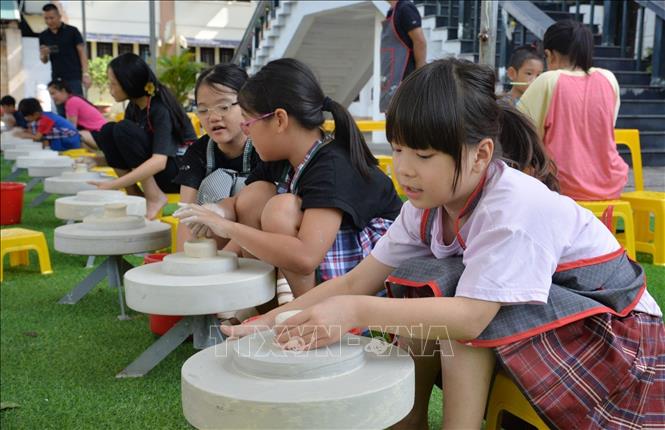 Học sinh thích thú trải nghiệm vuốt, nặn gốm trên các bàn xoay. Ảnh: Anh Tuấn - TTXVN