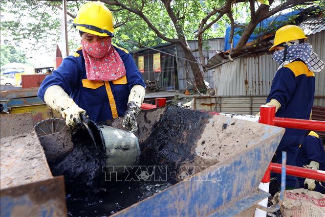 Công nhân Xí nghiệp Thoát nước số 2 nạo vét bùn đất, trục vớt rác thải để khơi thông dòng chảy tại khu vực mương thoát nước Dịch Vọng. Ảnh: Huy Hùng - TTXVN