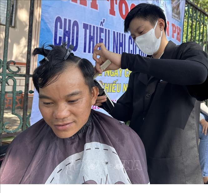 Tình nguyện viên cắt tóc miễn phí cho người nghèo. Ảnh: Lê Sen - TTXVN