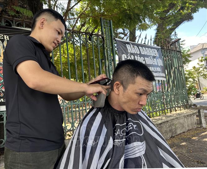 Tình nguyện viên cắt tóc miễn phí cho người nghèo. Ảnh: Lê Sen - TTXVN