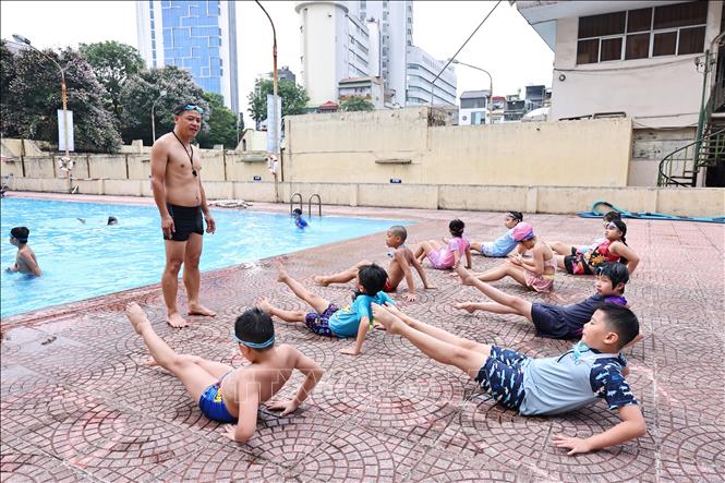 Huấn luyện viên hướng dẫn các động tác bơi đúng cách cho các em tại bể bơi Thái Hà. Ảnh: Minh Đức - TTXVN