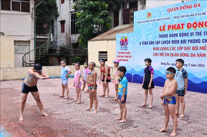 Huấn luyện viên hướng dẫn các động tác bơi đúng cách cho các em tại bể bơi Thái Hà. Ảnh: Minh Đức - TTXVN