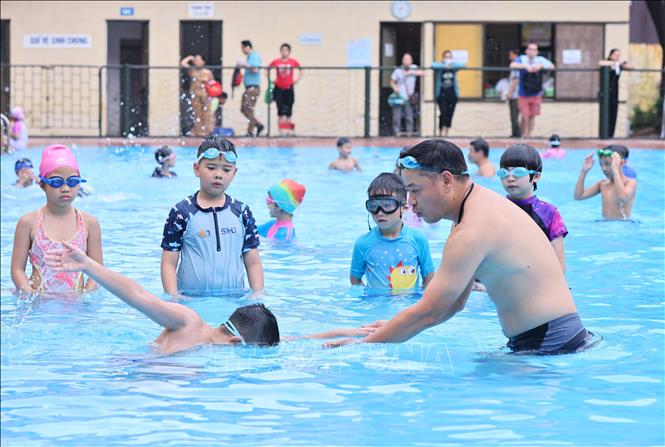 Huấn luyện viên hướng dẫn các động tác bơi đúng cách cho các em tại bể bơi Thái Hà. Ảnh: Minh Đức - TTXVN