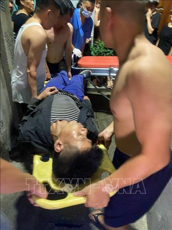 Lực lượng chức năng cùng người dân đưa nạn nhân đi cấp cứu. Ảnh: TTXVN
