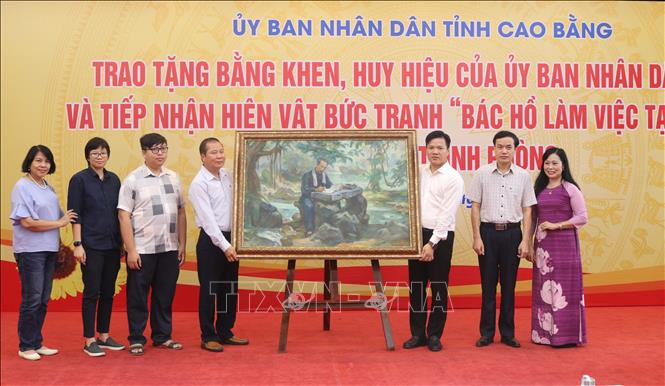Đại diện gia đình họa sĩ Trịnh Phòng trao tặng bức tranh cho tỉnh Cao Bằng. Ảnh: Chu Hiệu-TTXVN