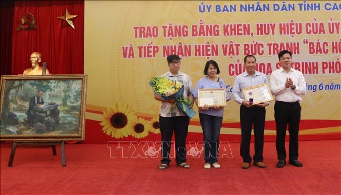 Phó Chủ tịch UBND tỉnh Cao Bằng trao Bằng khen cho đại diện gia đình họa sĩ Trịnh Phòng. Ảnh: Chu Hiệu-TTXVN
