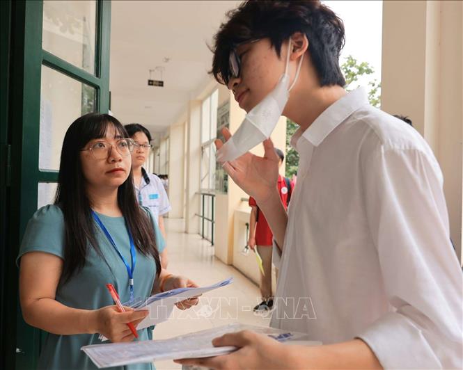 Giám thị điểm thi Trường THPT Thăng Long (quận Hai Bà Trưng) kiểm tra thông tin thí sinh. Ảnh: Hoàng Hiếu – TTXVN