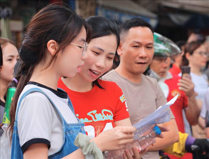 Thí sinh và phụ huynh xem đề bài thi môn Ngữ văn. Ảnh: Hoàng Hiếu - TTXVN