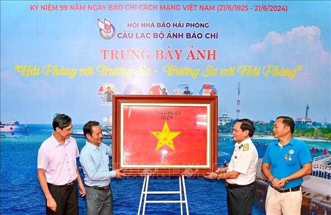 Chuẩn đô đốc Phạm Văn Luyện, Phó Chủ nhiệm Chính trị Quân chủng Hải quân trao cờ Tổ quốc tại Trường Sa tặng Hội Nhà báo Hải Phòng. Ảnh: Minh Huệ-TTXVN


