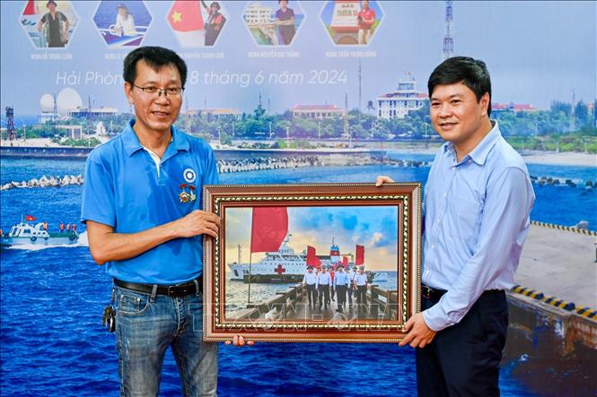 Phó Chủ tịch UBND thành phố Hải Phòng Hoàng Minh Cường nhận bức ảnh kỷ niệm do hội viên CLB Ảnh báo chí tác nghiệp trong chuyến công tác Trường Sa. Ảnh: Minh Huệ-TTXVN
