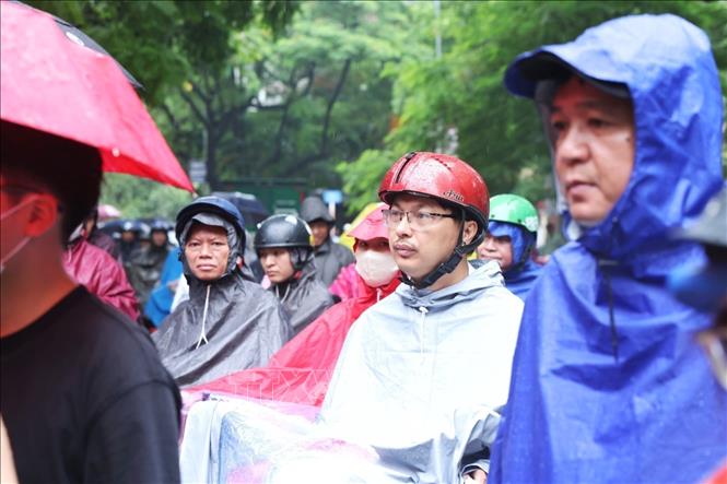 Người thân đội mưa ngóng đợi ngoài cổng trường trong ngày thi môn cuối cùng. Ảnh: Tuấn Anh - TTXVN