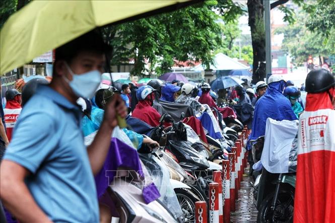 Người thân đội mưa ngóng đợi ngoài cổng trường trong ngày thi môn cuối cùng. Ảnh: Tuấn Anh - TTXVN