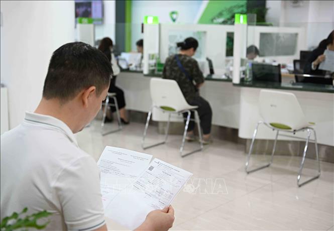 Khách hàng giao dịch nhận vàng tại Vietcombank 72 Trần Hưng Đạo, Hà Nội. Ảnh: Trần Việt - TTXVN