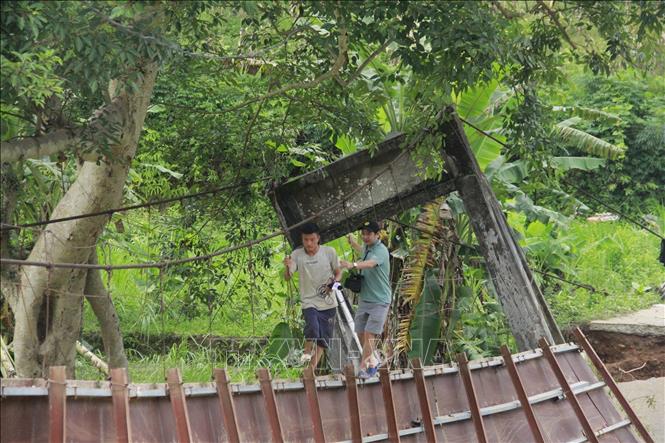 Việc đi vào thôn Lũng Cáng trên chiếc cầu treo bị lũ cuốn, hư hỏng nặng giờ hết sức khó khăn, nguy hiểm. Ảnh: TTXVN phát