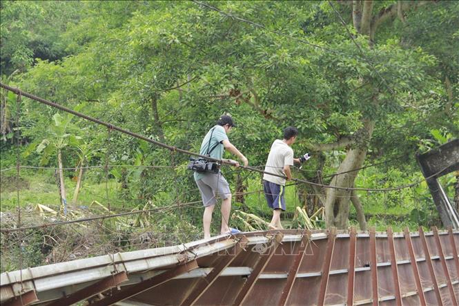 Việc đi vào thôn Lũng Cáng trên chiếc cầu treo bị lũ cuốn, hư hỏng nặng giờ hết sức khó khăn, nguy hiểm. Ảnh: TTXVN phát
