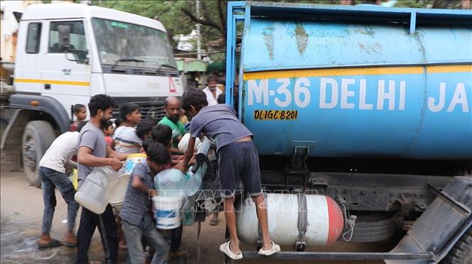 Người dân đu bám lấy nước ngay cả khi xe bồn chưa dừng lại. Ảnh: Ngọc Thúy - P/v TTXVN tại Ấn Độ