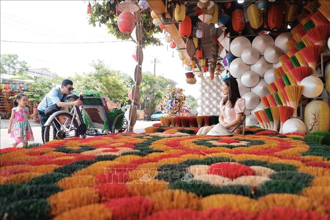 A visitor and her family take photos at a shop in Thuy Xuan incense village. VNA Photo