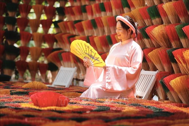 A tourist takes check-in photos with Thuy Xuan incense sticks. VNA Photo